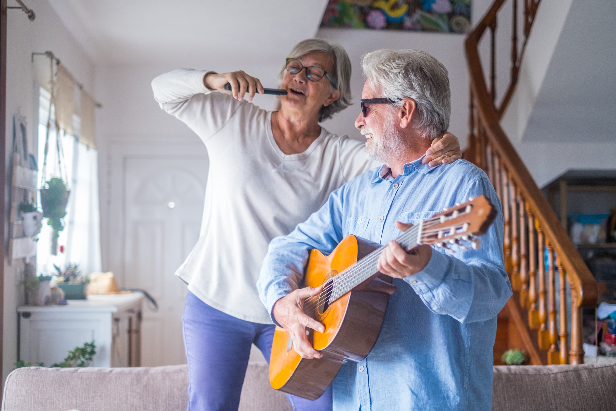 Couple of two happy seniors or mature and old people singing and dancing together at home Couple of two happy seniors or mature and old people singing and dancing together at home