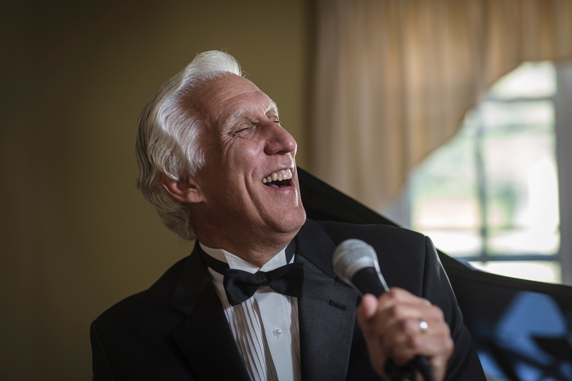 Senior man in bow tie singing into microphone